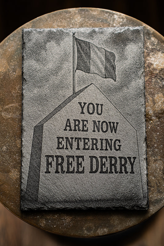 Stone plaque with 'You are now entering Free Derry' text and a flag on a dark background